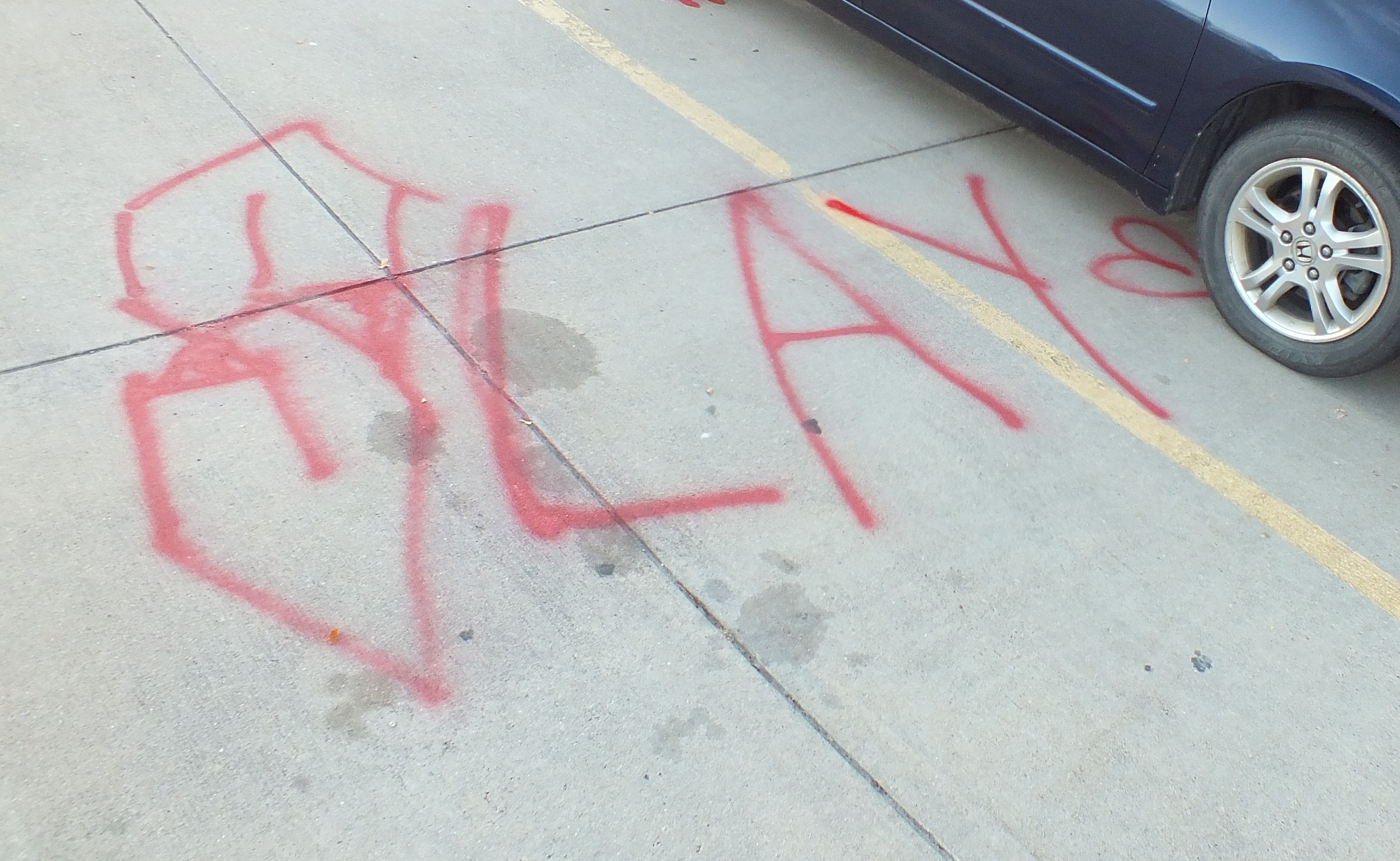 Image 2: red graffiti on pavement that says 