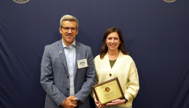 Amanda Duhon holding her award standing next to Gordon McLaughlin against a blue background