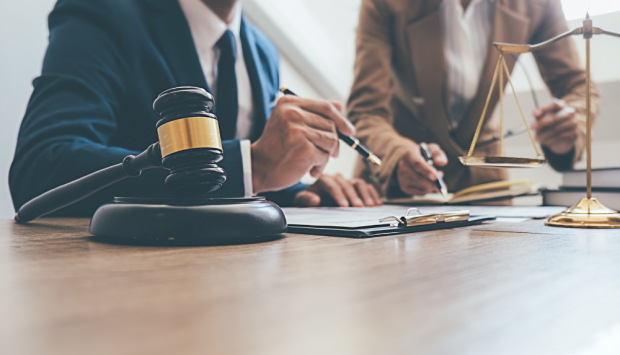 Two adults review paperwork next to a gavel and scales