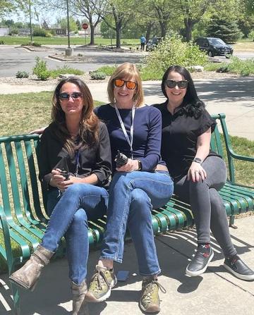 Three SummitStone Health Partners co-responder clinicians sit on a bench outside Loveland Police Department.