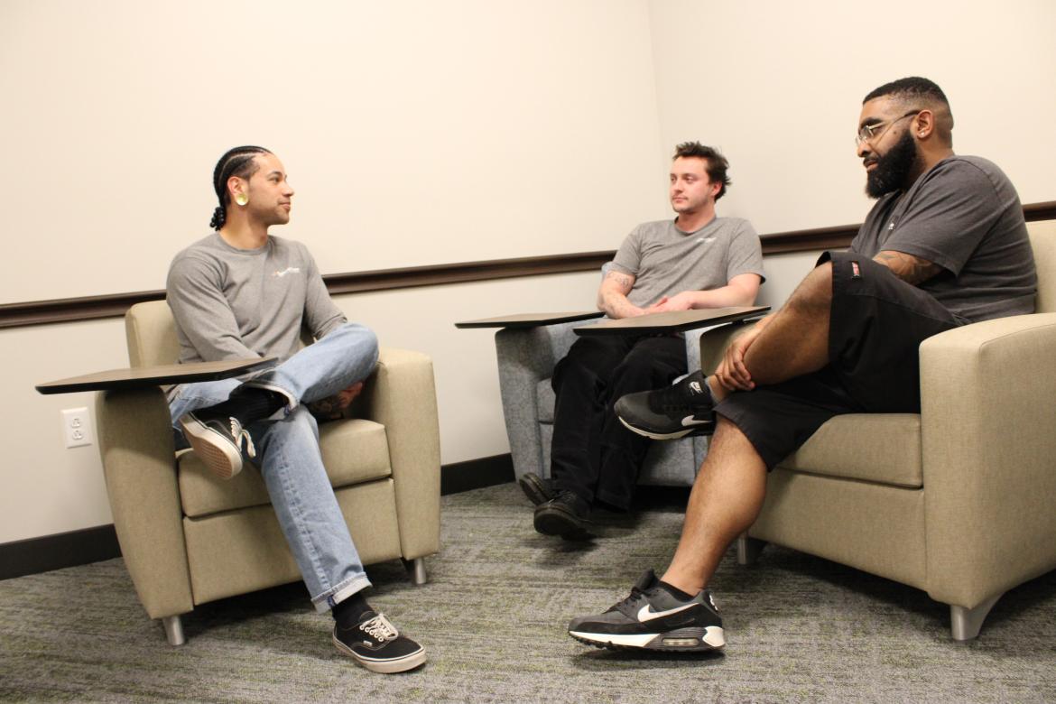 Three SummitStone Health Partners peer specialists sit in chairs and talk at the Acute Care facility at Longview campus.