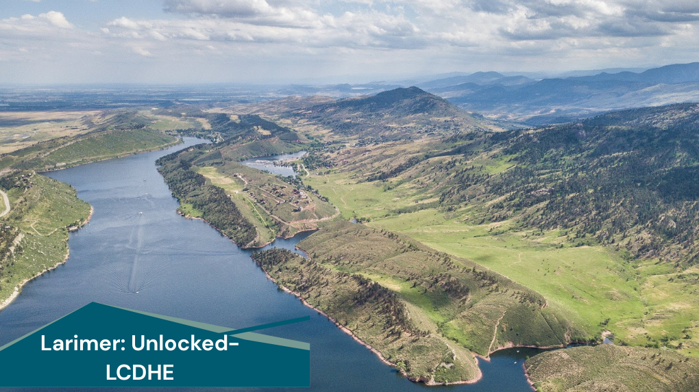 Aerial view of a large reservoir winding through rolling green hills and rugged mountain terrain under a partly cloudy sky. The water stretches into the distance, bordered by open grasslands, rocky slopes, and scattered vegetation. In the lower left corner, a teal graphic banner displays the text: “Larimer: Unlocked – LCDHE.”