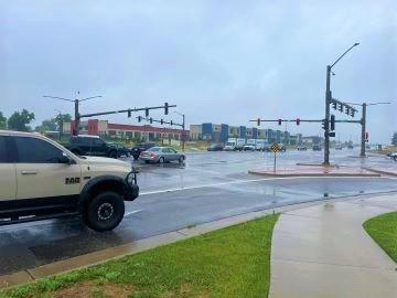 Intersection of Highway 287 with a sidewalk and traffic signals, shown under rainy weather conditions