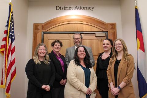 Six adults with the Larimer County Juvenile Diversion Program pose for a photo in front of the District Attorney's office.
