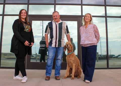 From left to right, Madi Montes, Steffen Essen, Remi the service dog, and the Acute Care facility at Longview campus, between the cities of Loveland and Fort Collins.Jamie Powell pose for a photo in front of the 