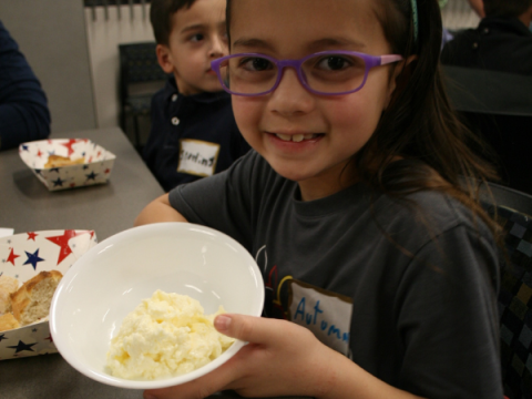 A cloverbud shows off the butter she helped make.