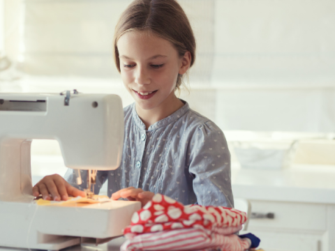 A child sews something at a sewing machin