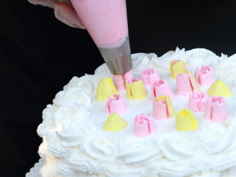 Un pastel decorado con glaseado blanco, amarillo y rosa.