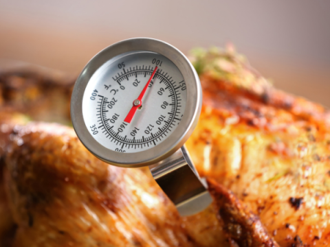 A thermometer tests the temperature of poultry being cooked