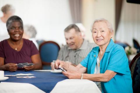 Oudere volwassenen spelen kaart aan een ronde tafel