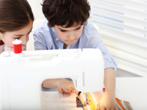 Un niño cose algo en una máquina de coser.