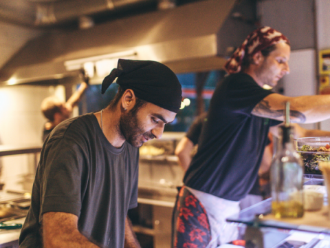 Dois funcionários preparam comida em um restaurante.