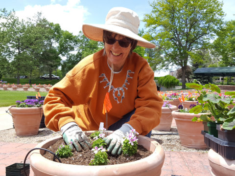 A Master Gardener plants something in a very large planter