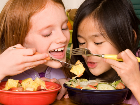 Two children enjoy a bowl of food
