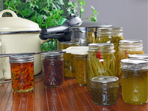 Food Preservation A group of canned goods with a pressure cooker in the background