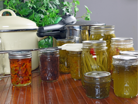 A group of canned goods with a pressure cooker in the background