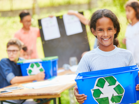 Two teenagers hold recycling bins