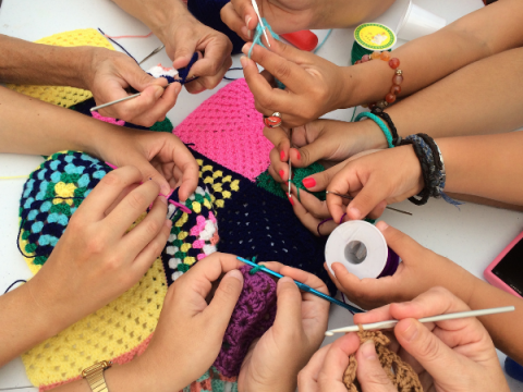 Multiple children work on crocheting something at the same time.