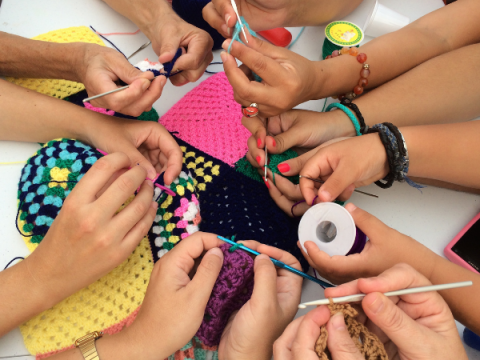 Varios niños trabajan en crochet algo al mismo tiempo.