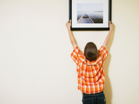 A child hangs a picture frame