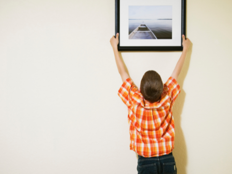 Un bambino appende una cornice