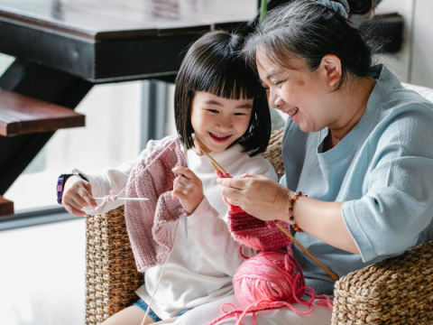 おばあさんが孫娘と編み物をする