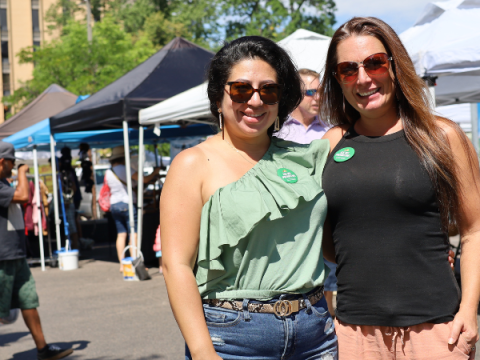 Två marknadsambassadörer står på Larimer County Farmers' Market