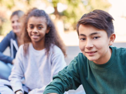 Two youth sit outside and look at the camera.