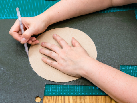 Someone cuts a circle out of leather