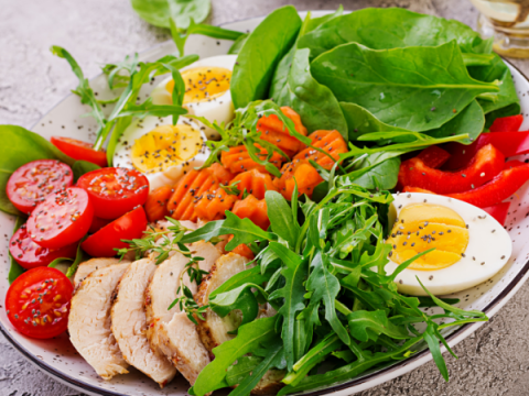 Ein gesund aussehender Salat mit gemischtem Blattgemüse, einem gekochten Ei, Tomaten, Paprika usw.