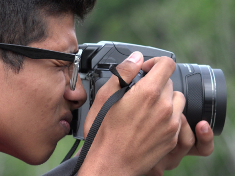 एक किशोर फोटो लेने के लिए एसएलआर कैमरे का उपयोग करता है