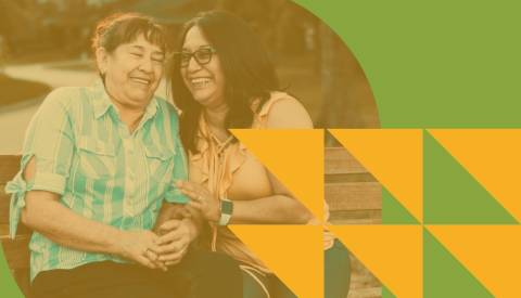 高齢者と介護者が一緒に笑います。写真はオレンジと緑のグラフィックでオーバーレイされます。