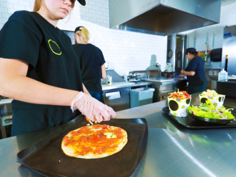 Tres empleados preparan comida en un restaurante