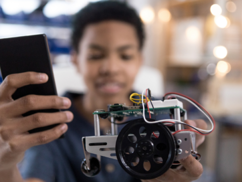 A teenager works on an electronic component with a motor