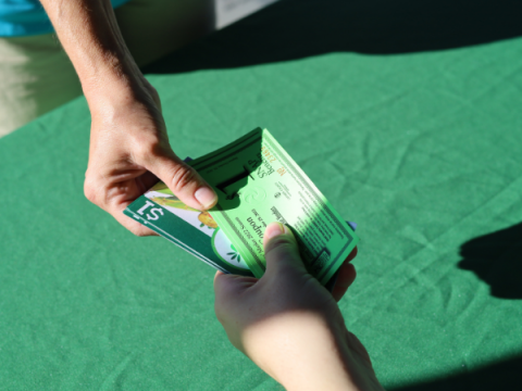 A Farmers Market volunteer hands someone SNAP vouchers and Double Up Bucks