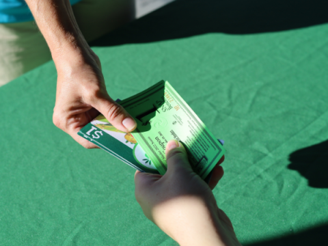 Um voluntário do Farmers Market entrega a alguém vouchers SNAP e Double Up Bucks