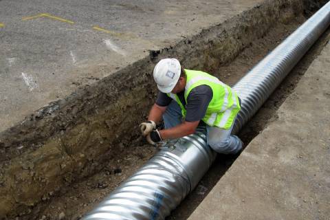 A Larimer County employee tightening a band used to connect two sections of culvert.