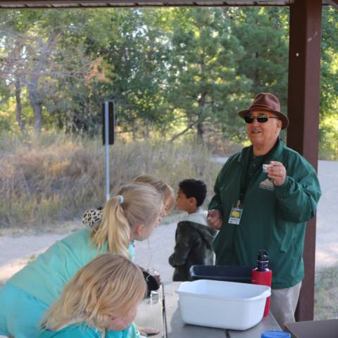 Volunteer teaching elementary age kids a nature based program at picnic shelter.