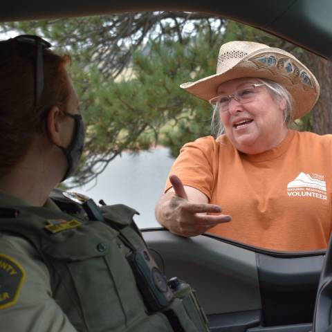 Volunteer talks to a Ranger sitting in her truck.