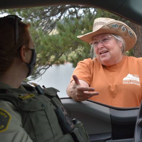 Volunteer campground host talking to Park Ranger through vehicle window.