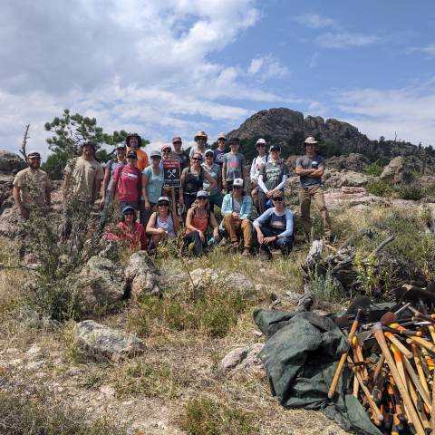 Group of people gathered next to hiking trail after completing a project.