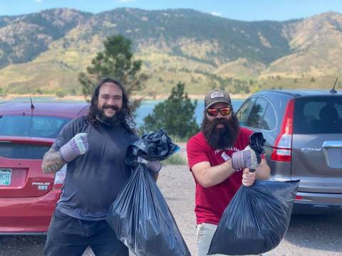 Twee vrijwilligers laten trots de vuilniszakken zien die ze hebben gevuld terwijl ze zwerfafval opraapten bij Horsetooth Reservoir.