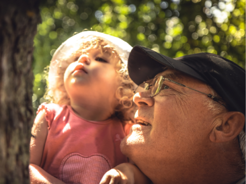 A grandpa helps his grandchild explore bugs on a tree