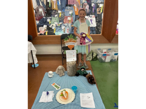 A Larimer County 4-H Member at the State Creative Cooks Competition A Larimer County 4-H Member at the State Creative Cooks Competition. Her display is spread out in front of hear and is bunny/ carrot themed.