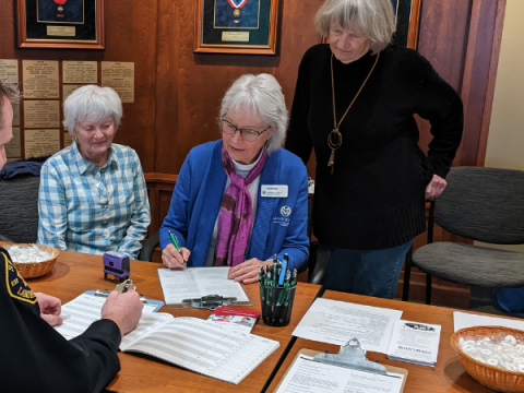 Three members of the Advance Care Planning team assist someone fill out their documents.