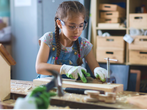 A young girl uses a hand planer