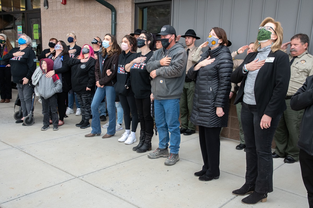 Image 3: Family and staff together watch as flag is raised for Memorial Dedication, courtesy Charlie Johnson